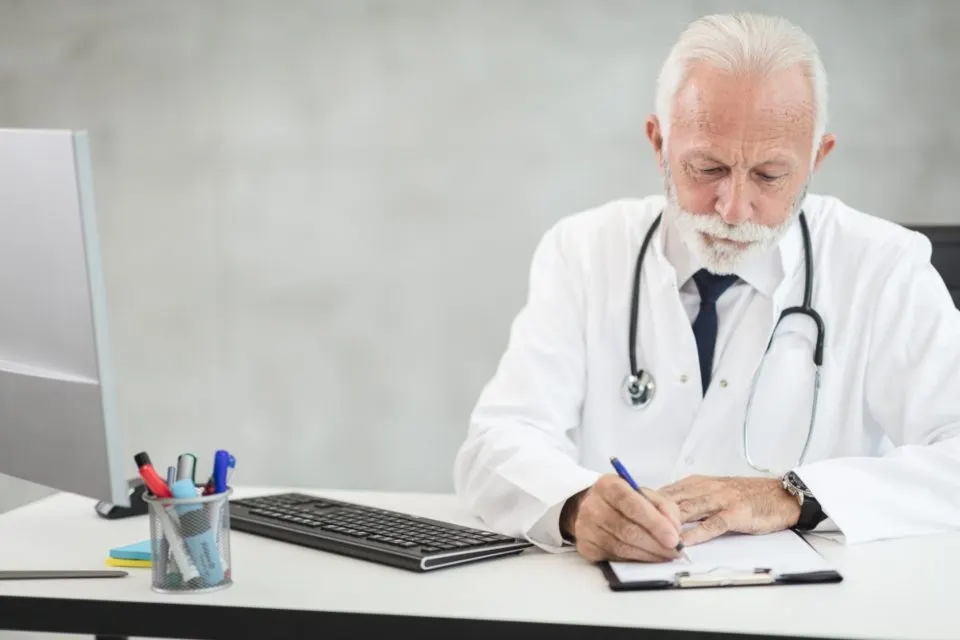 Physician reviewing paperwork at his desk